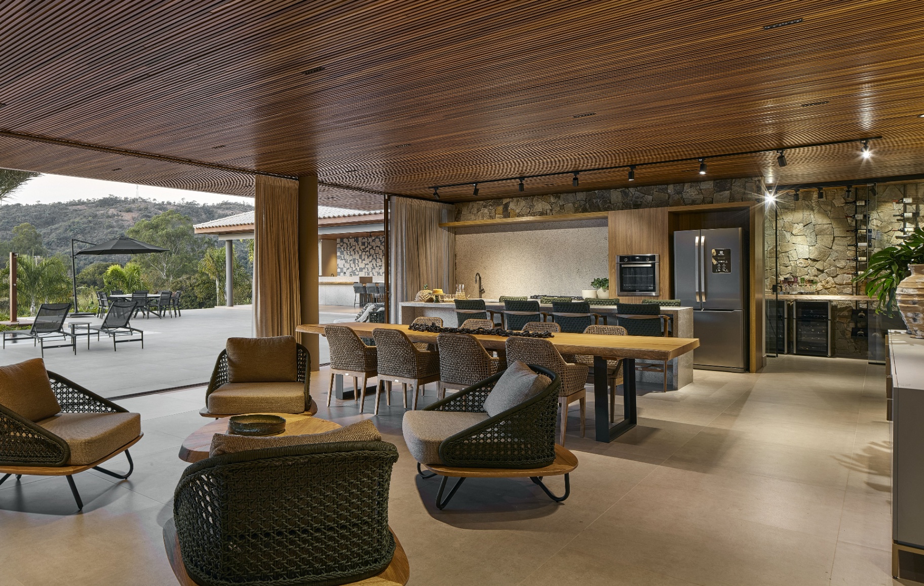 Poltronas Armani em trançado verde integradas à sala de jantar e cozinha gourmet