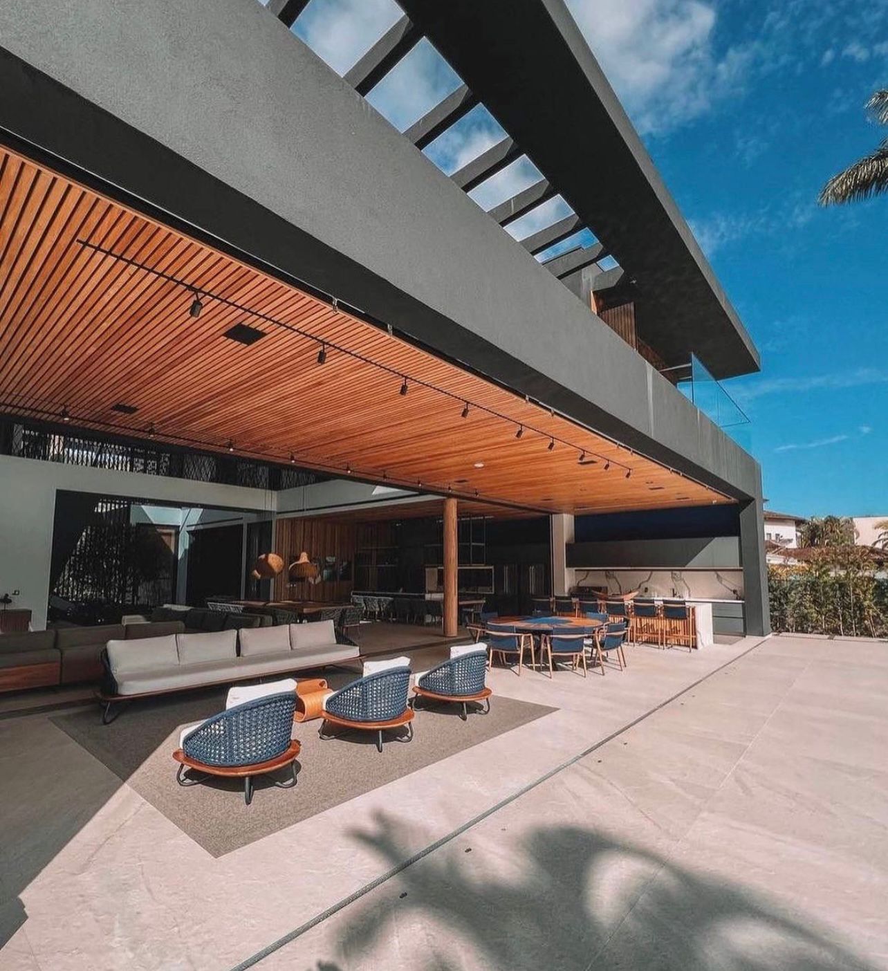 Sofá e poltronas Armani em varanda gourmet com pé-direito alto